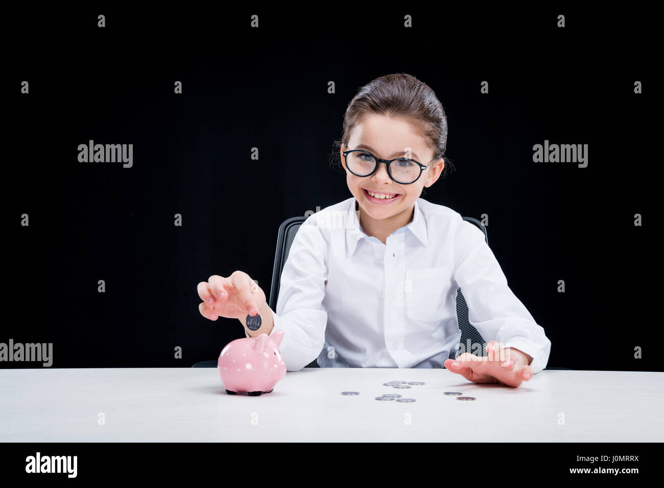 Smiling girl in formal wear putting coin into piggy bank Stock Photo ...