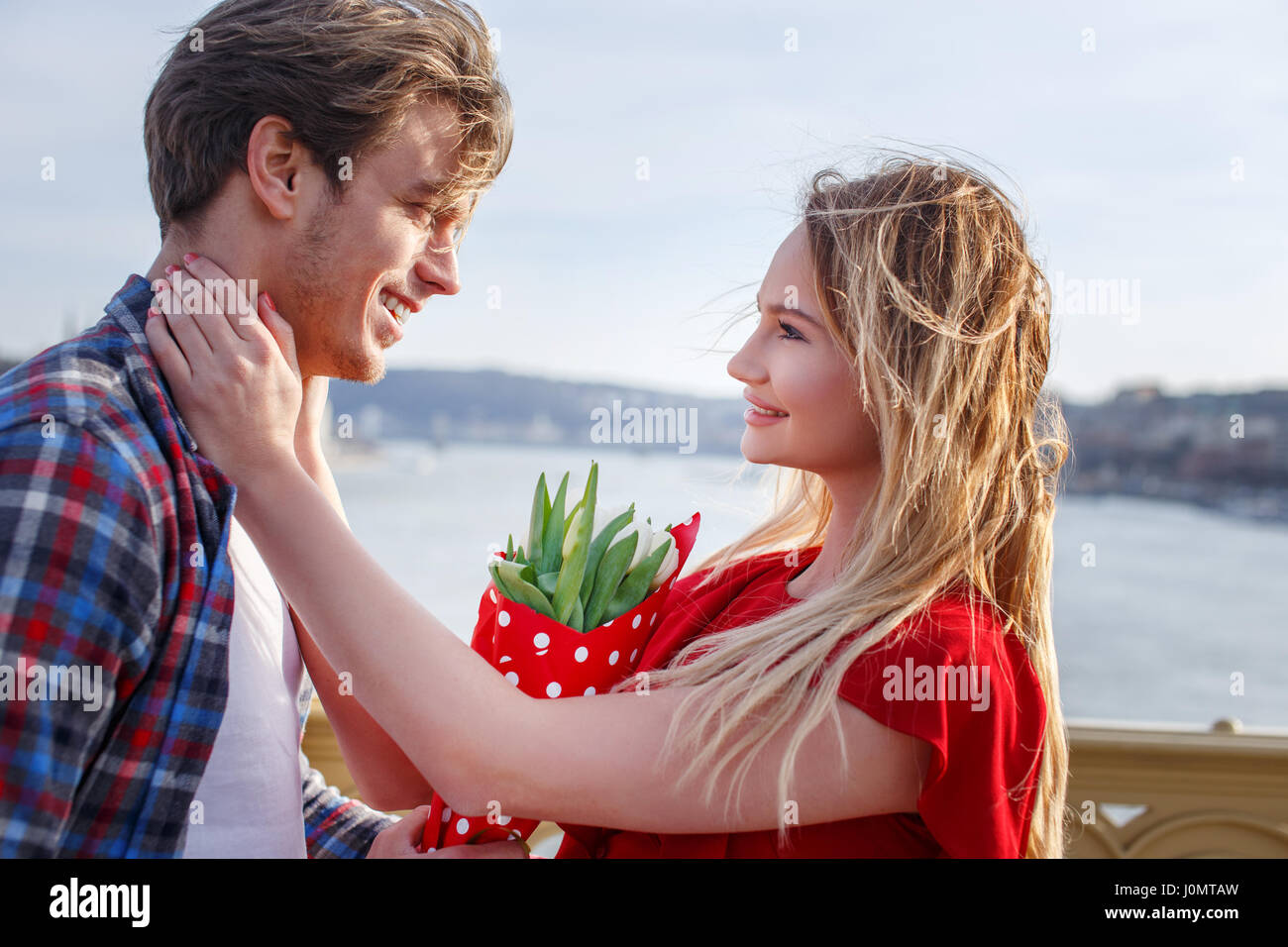 Young woman got bouquet on dating from man on bridge over the river Stock Photo