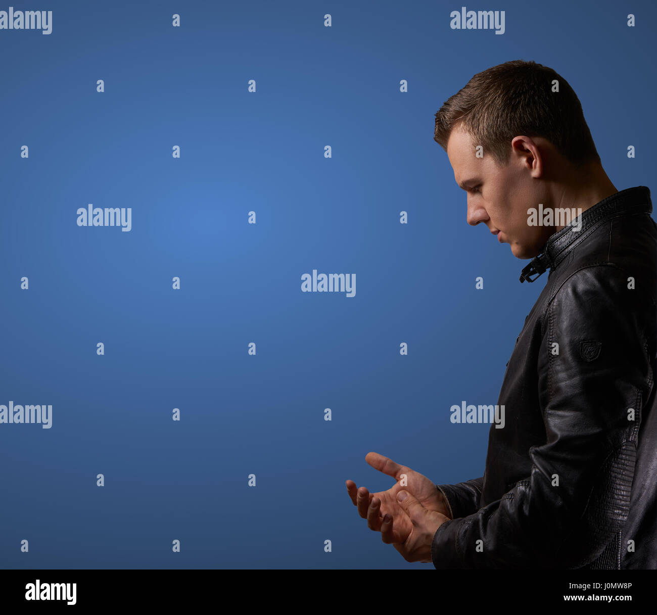 Profil shot from a young man in leatherjacket, rubbing his hand with copyspace Stock Photo