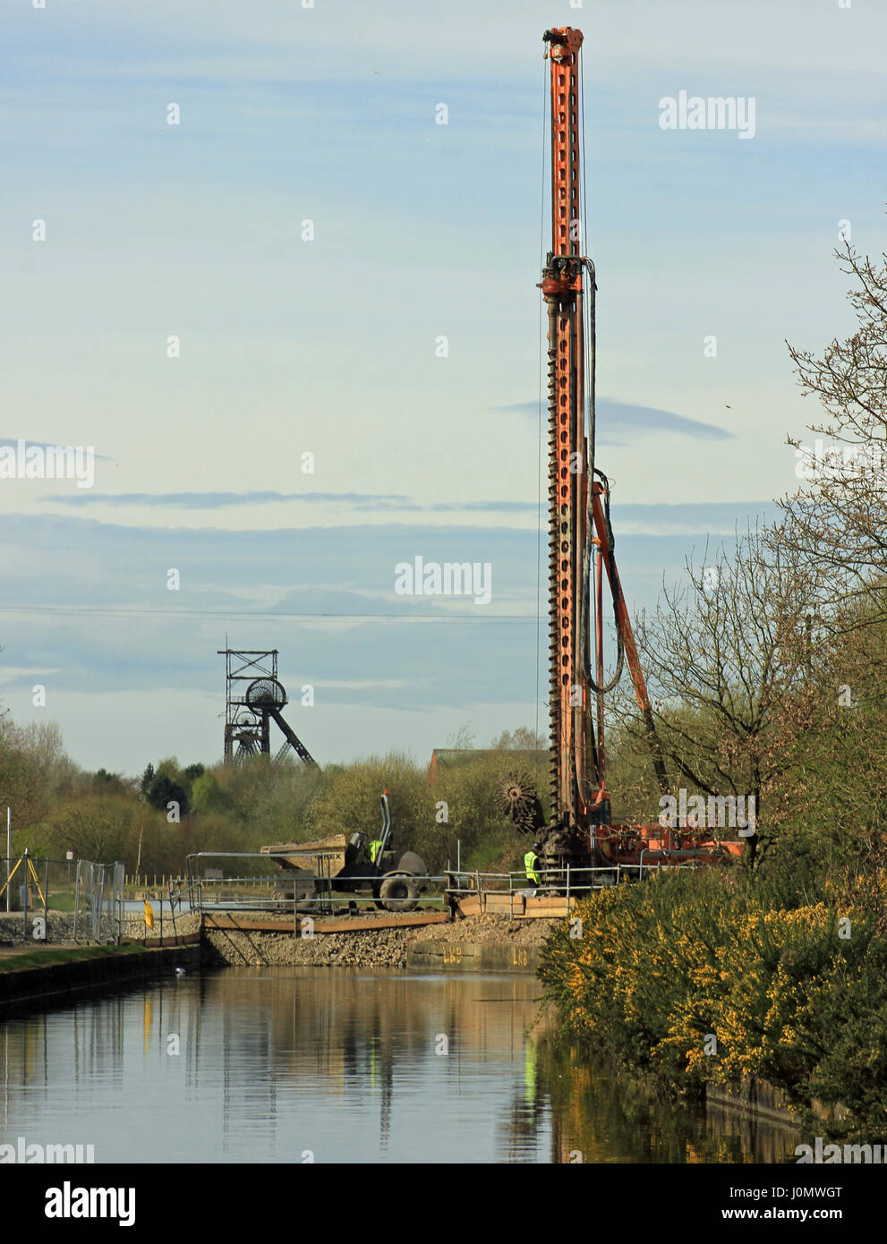 Bridge replacement works over the Bridgewater canal with large machinery at work while in the distance is the last pit head gear in Lancashire. Stock Photo