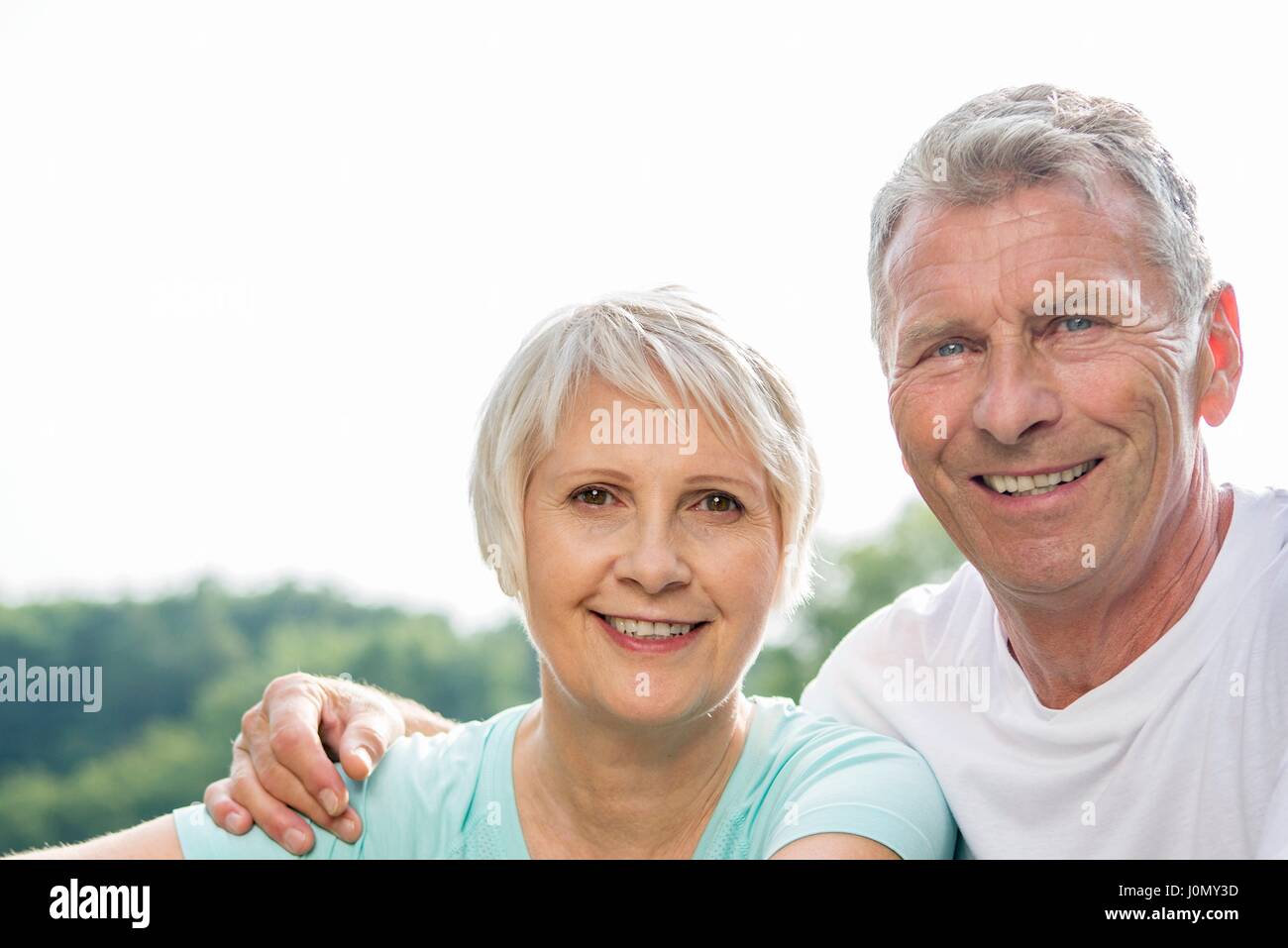 Senior couple smiling towards camera, man with arm around woman. Stock Photo