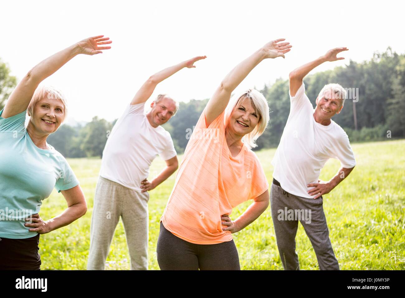 Four people in field exercising. Stock Photo