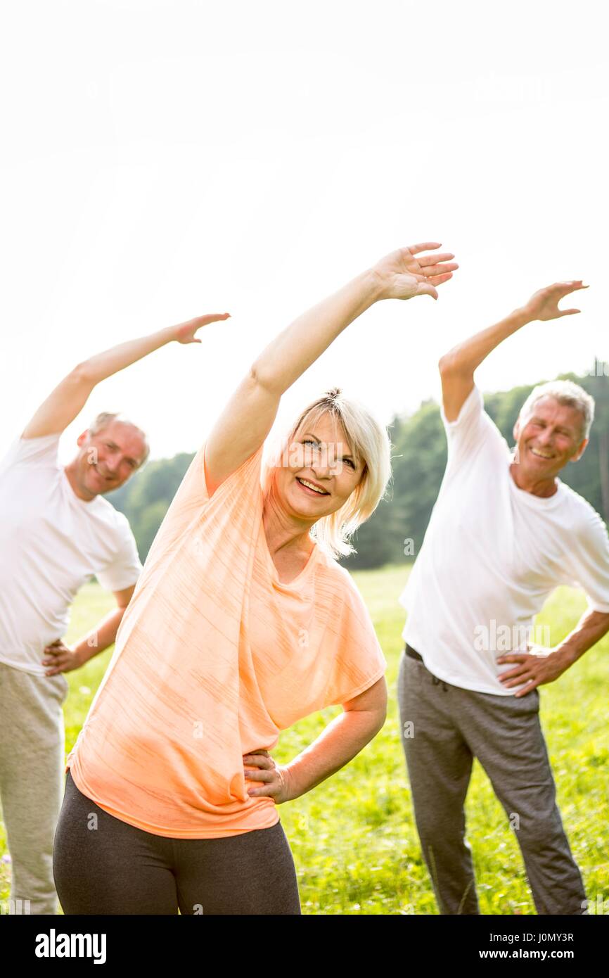 Three people stretching with arms up. Stock Photo