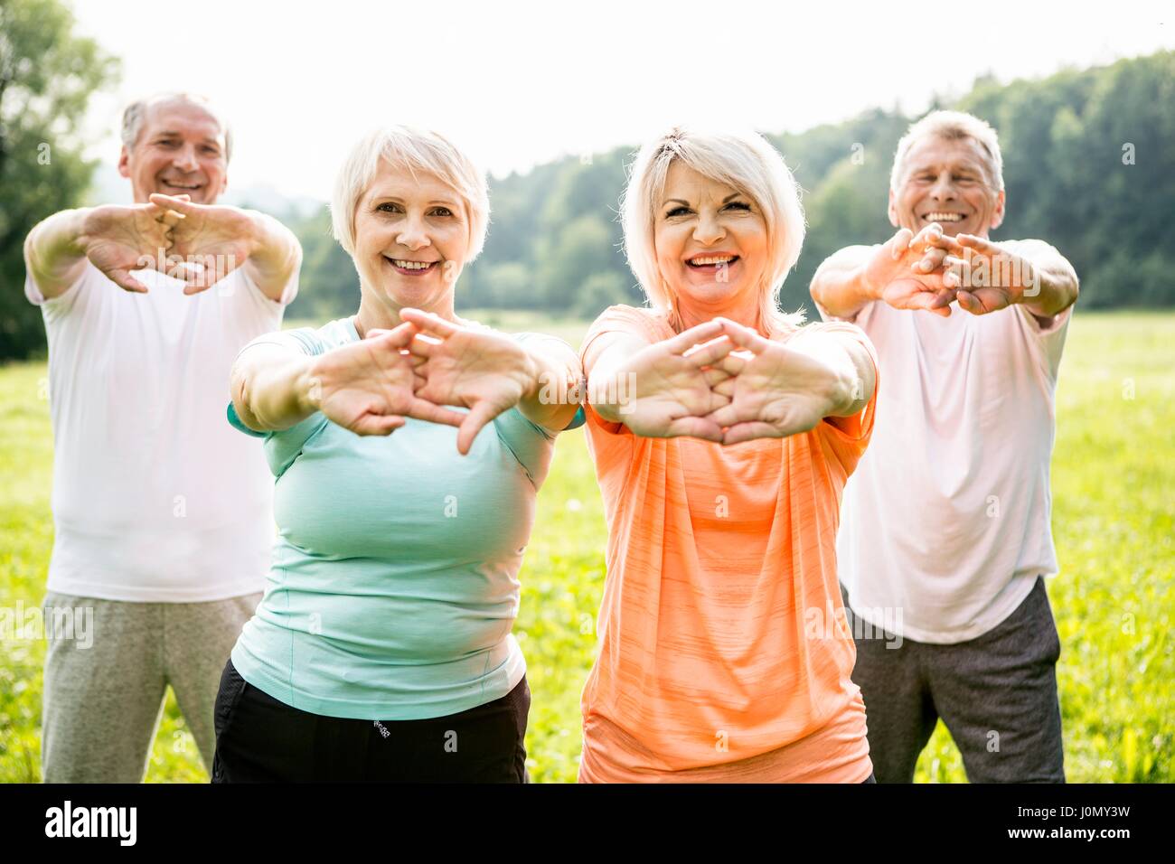 Four people exercising with arms outstretched. Stock Photo