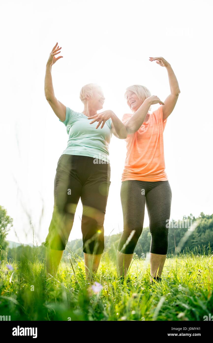 Two women exercising with arms raised. Stock Photo