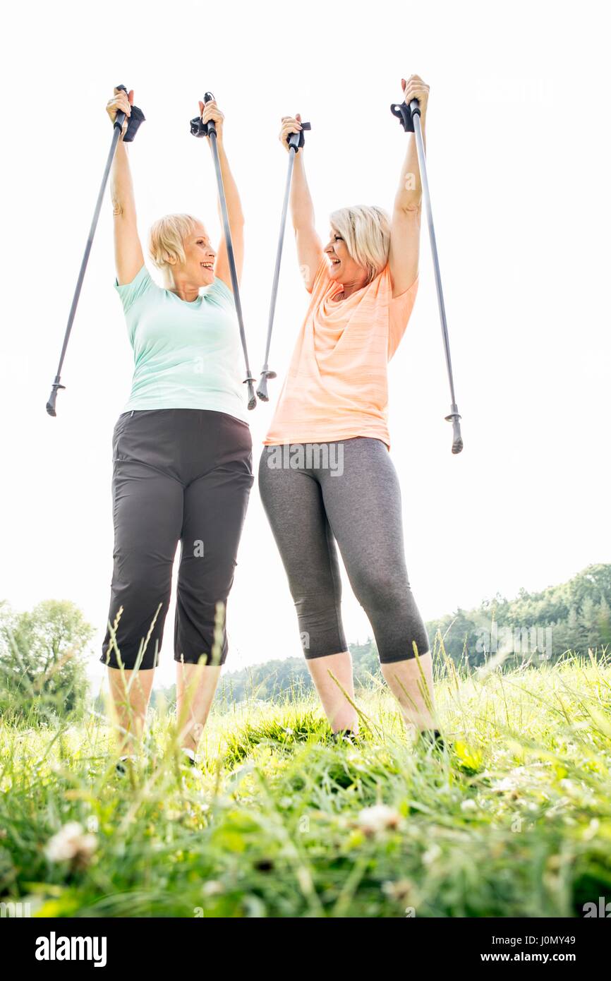 Two women with walking poles raised in air. Stock Photo