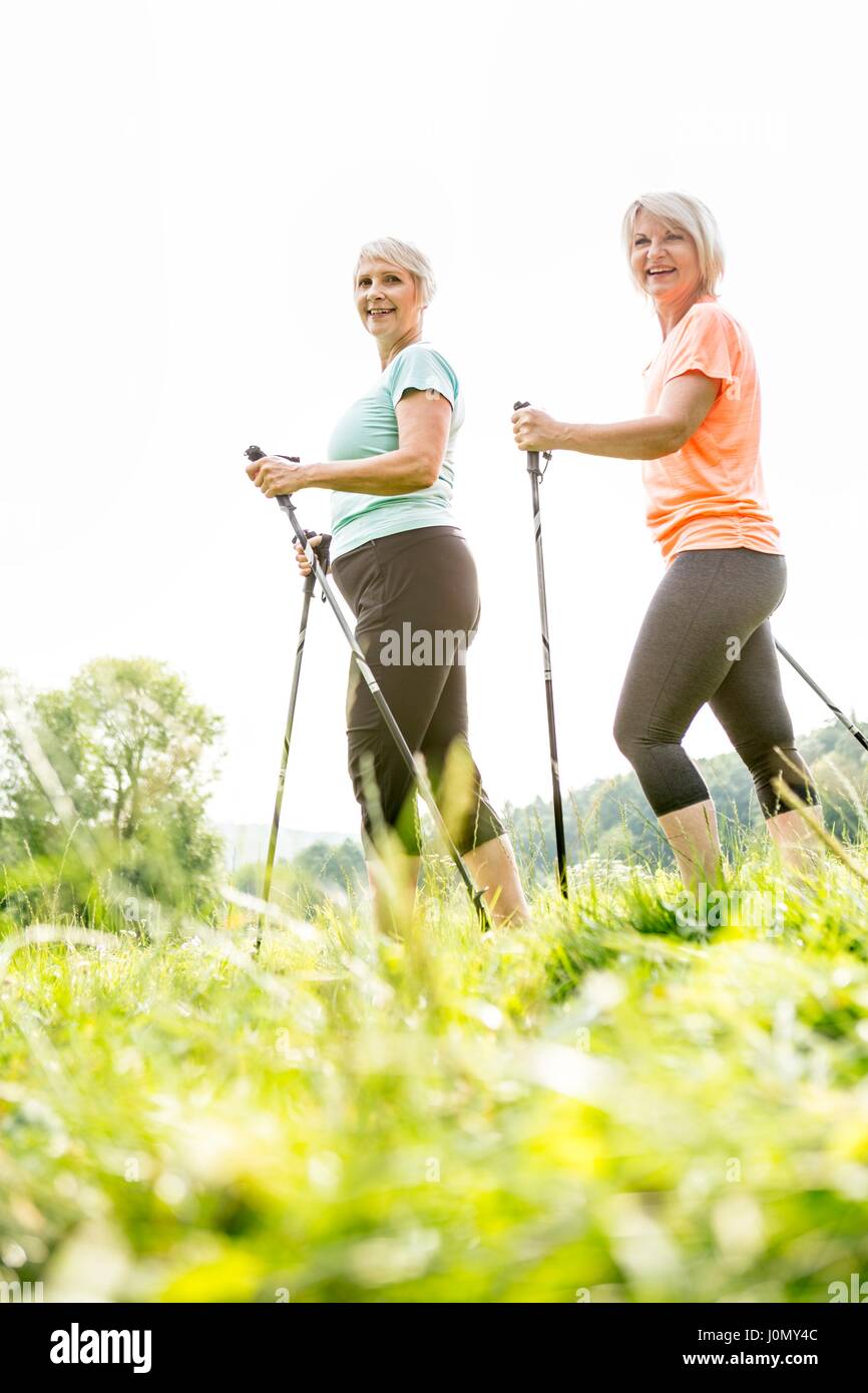 Two women walking in grass with walking poles. Stock Photo