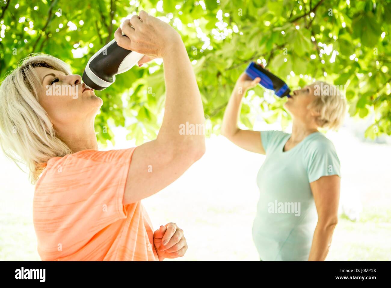 Two women drinking water from sports bottles. Stock Photo