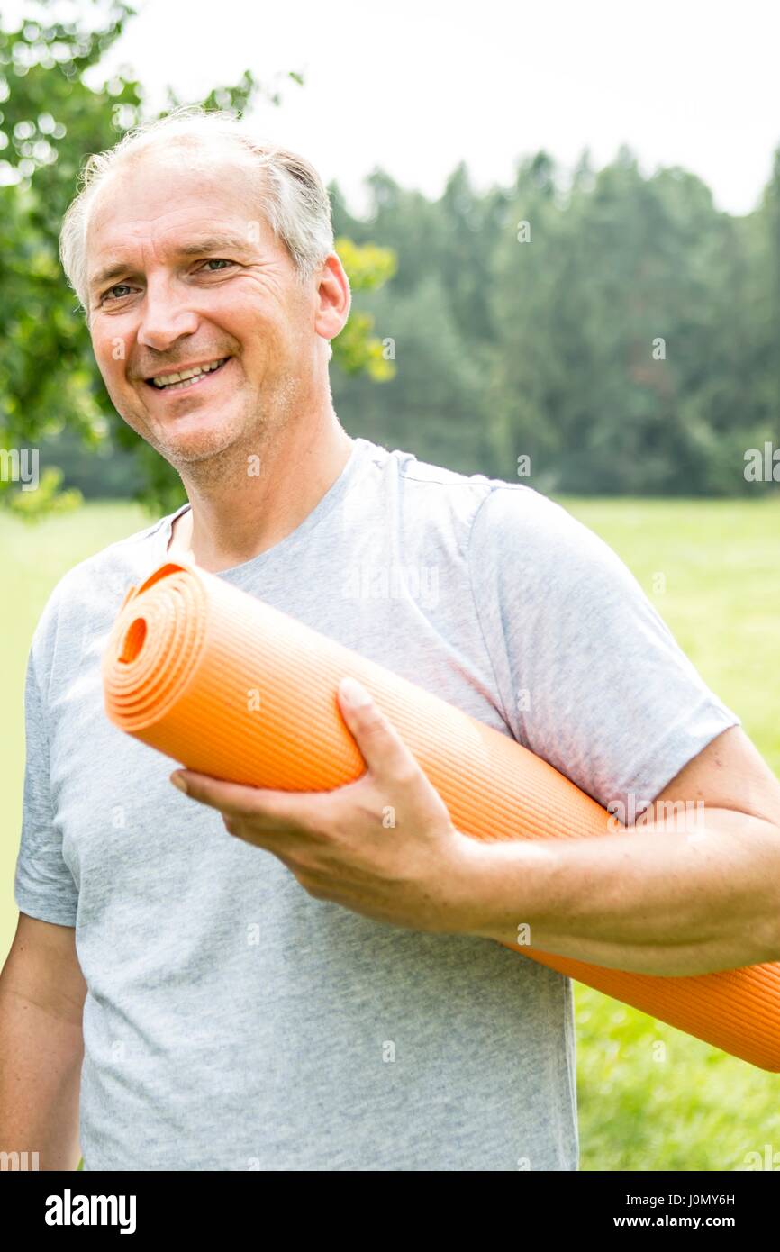 Man with yoga mat, smiling. Stock Photo