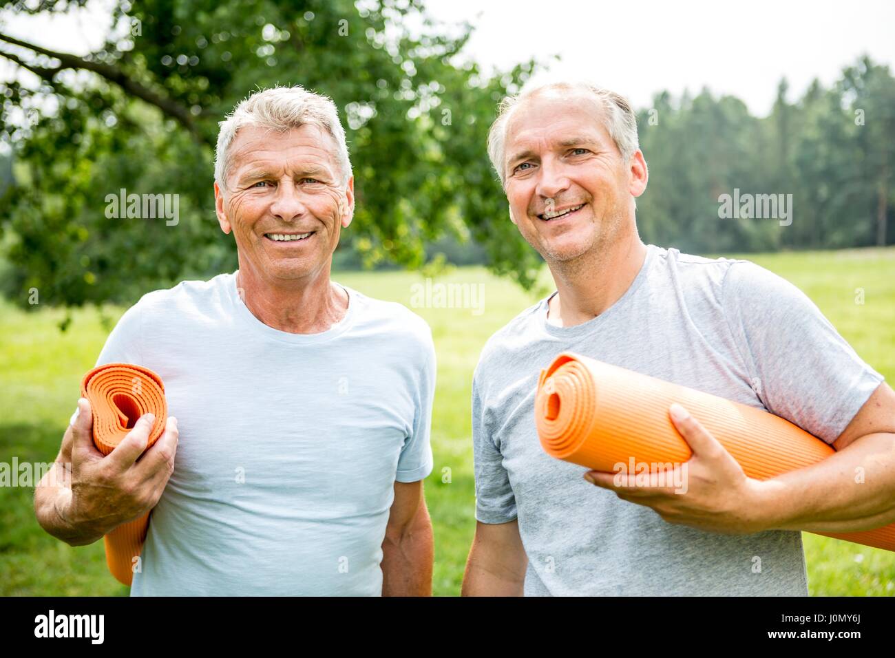 Two men with yoga mats, smiling. Stock Photo