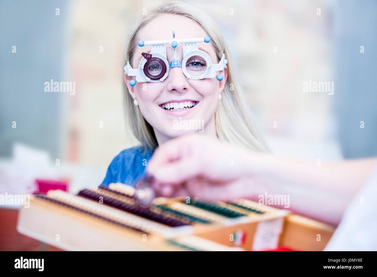 Portrait of cheerful young woman wearing trial frame in optometrist's shop, close-up. Stock Photo