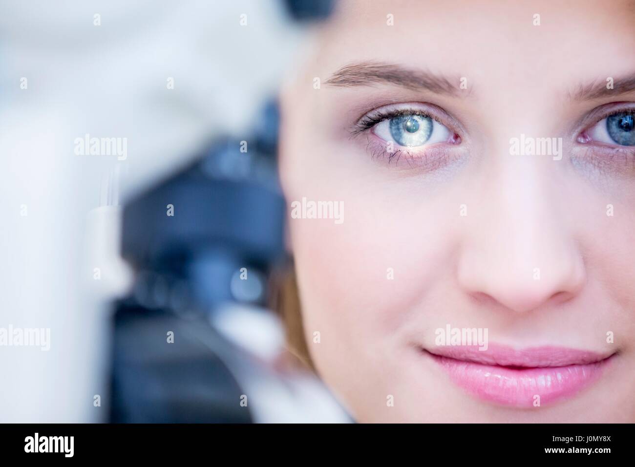 Woman sitting in front of slit lamp for eye examination. Stock Photo