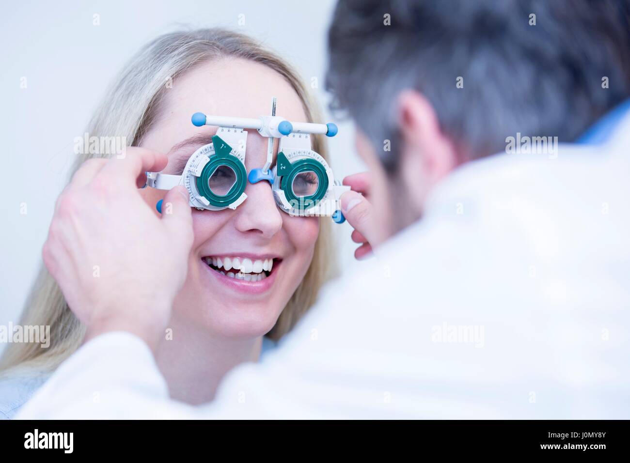 Optometrist performing eye test of young woman. Stock Photo