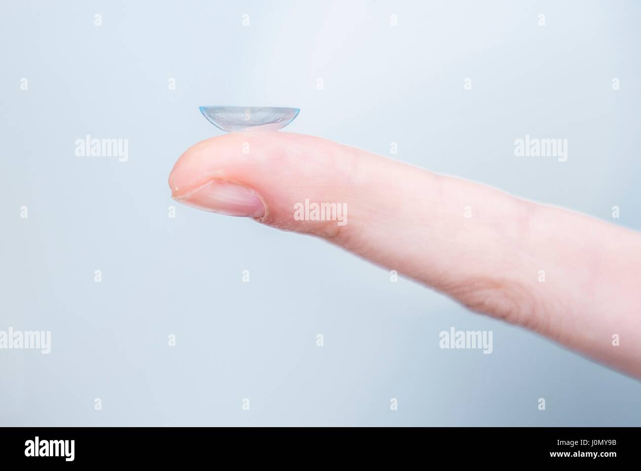 Close-up of person holding contact lens on finger. Stock Photo