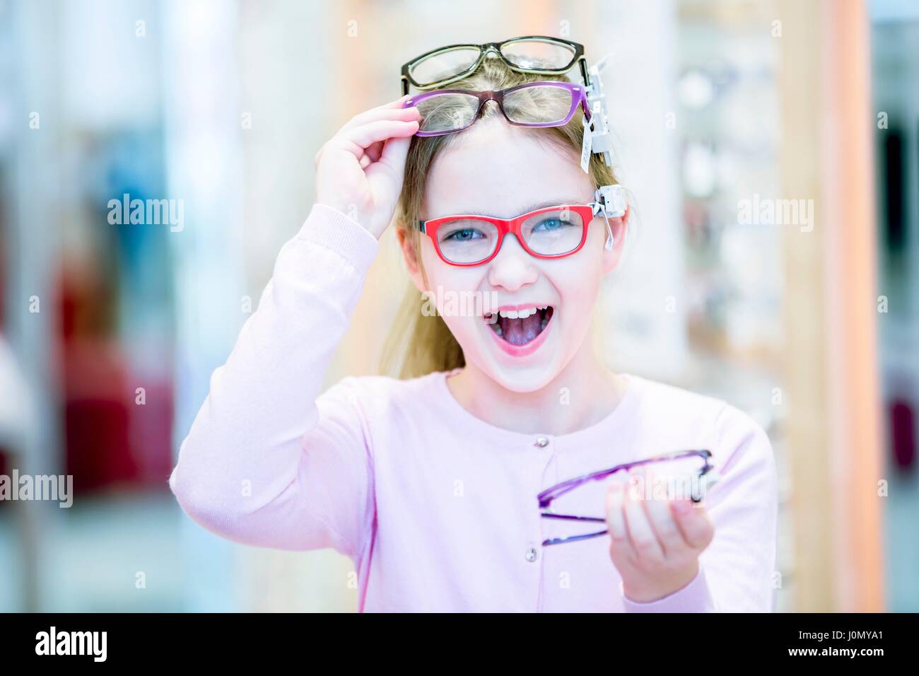 Portrait of girl trying glasses in optometrist's shop. Stock Photo