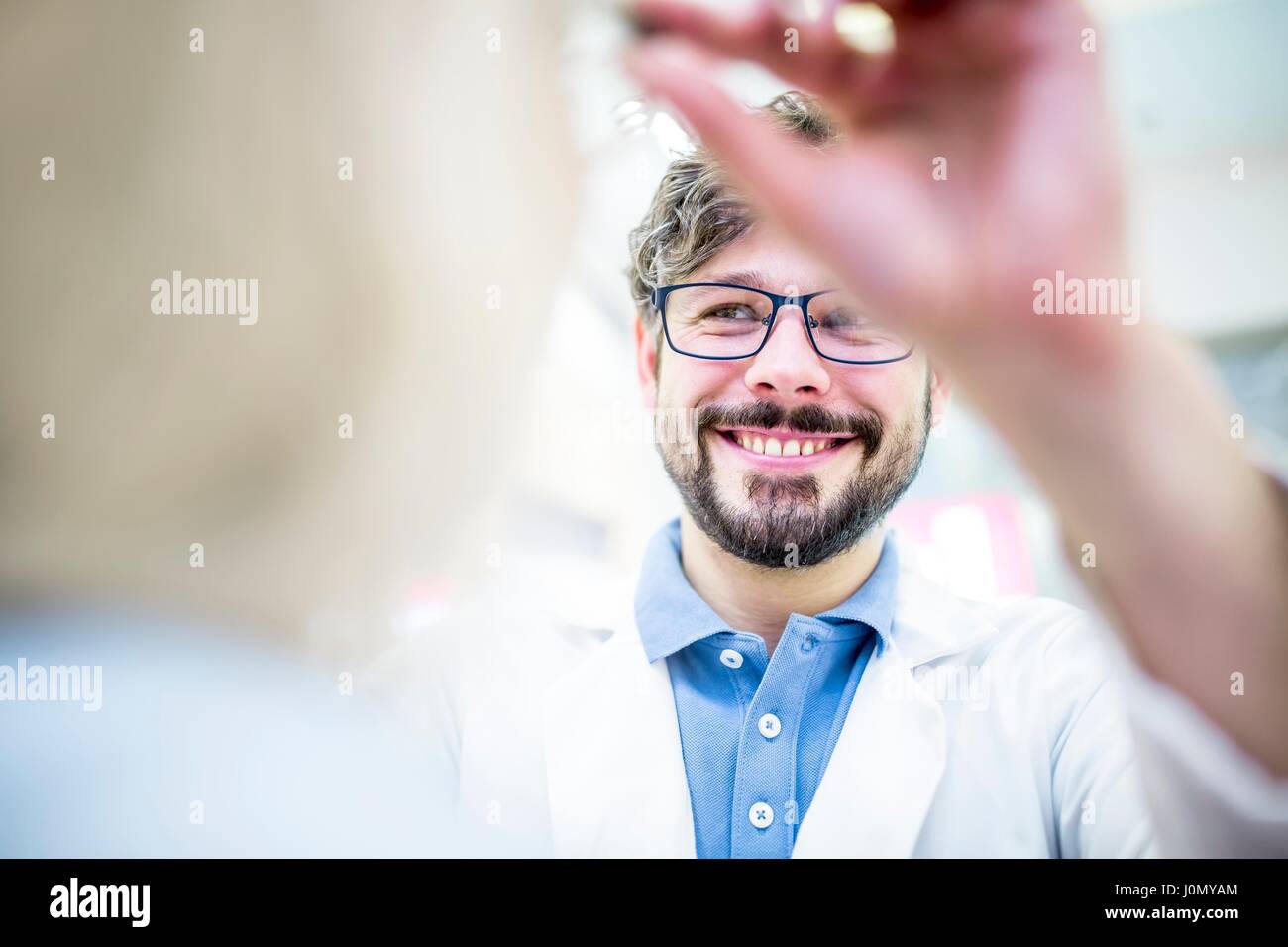 Optometrist trying glasses on woman in optometrist's shop. Stock Photo