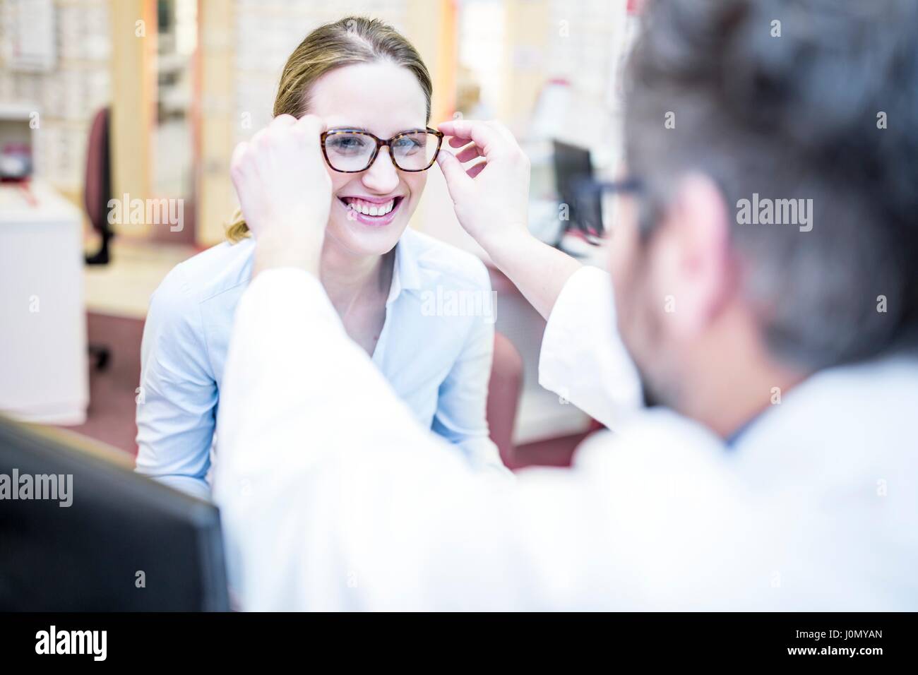Optometrist trying glasses on woman in optometrist's shop. Stock Photo