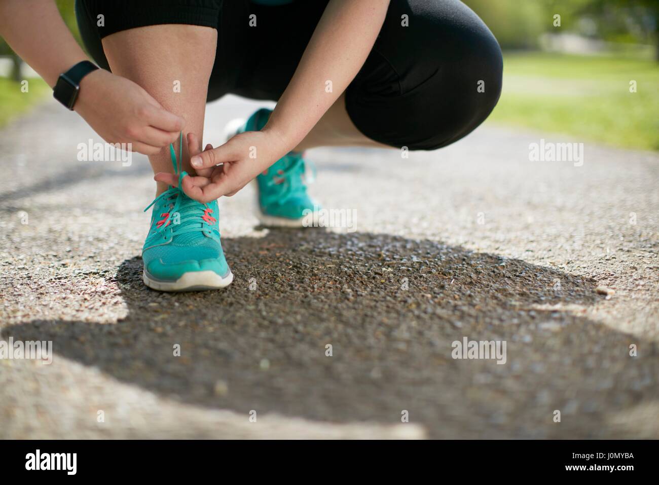 Woman crouching, tying up trainers. Stock Photo