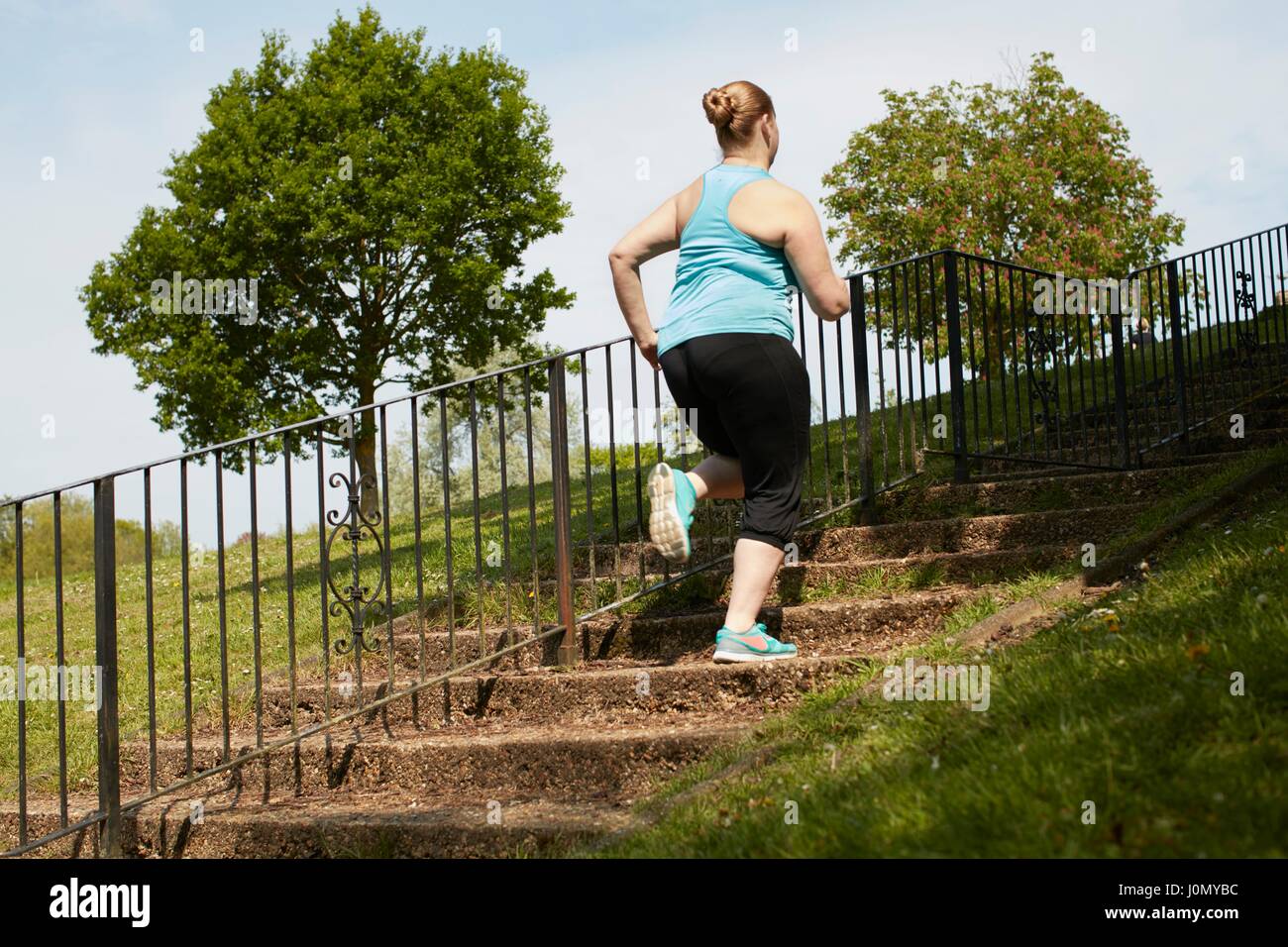 Young woman running up steps. Stock Photo