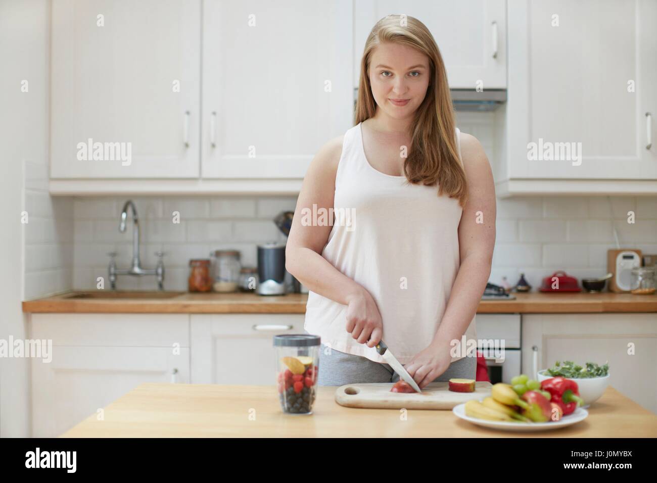 Young woman preparing healthy food in kitchen. Stock Photo