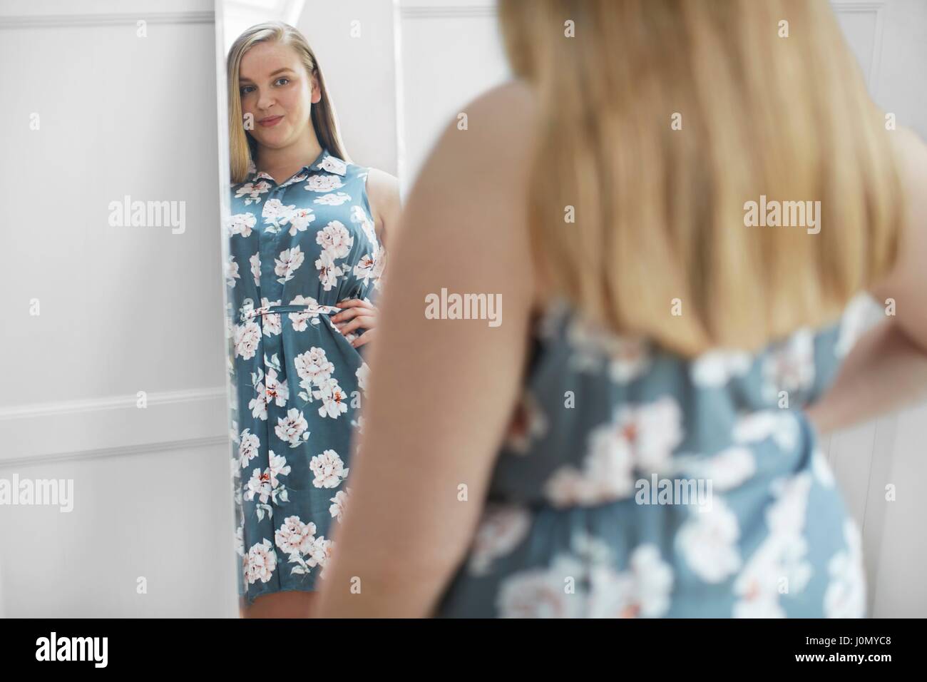 Young woman looking at reflection in mirror, smiling. Stock Photo