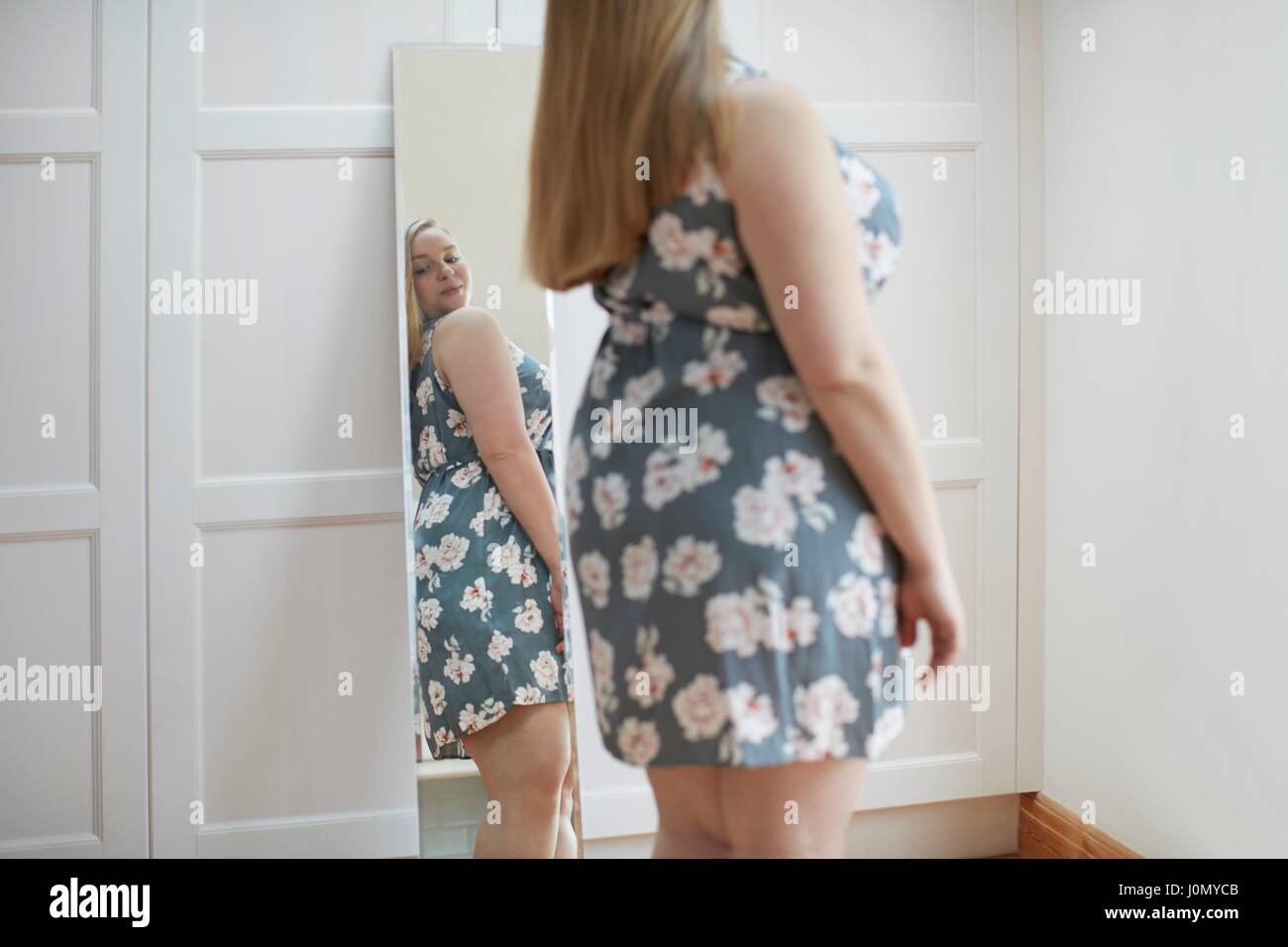 Young woman looking at reflection in mirror. Stock Photo