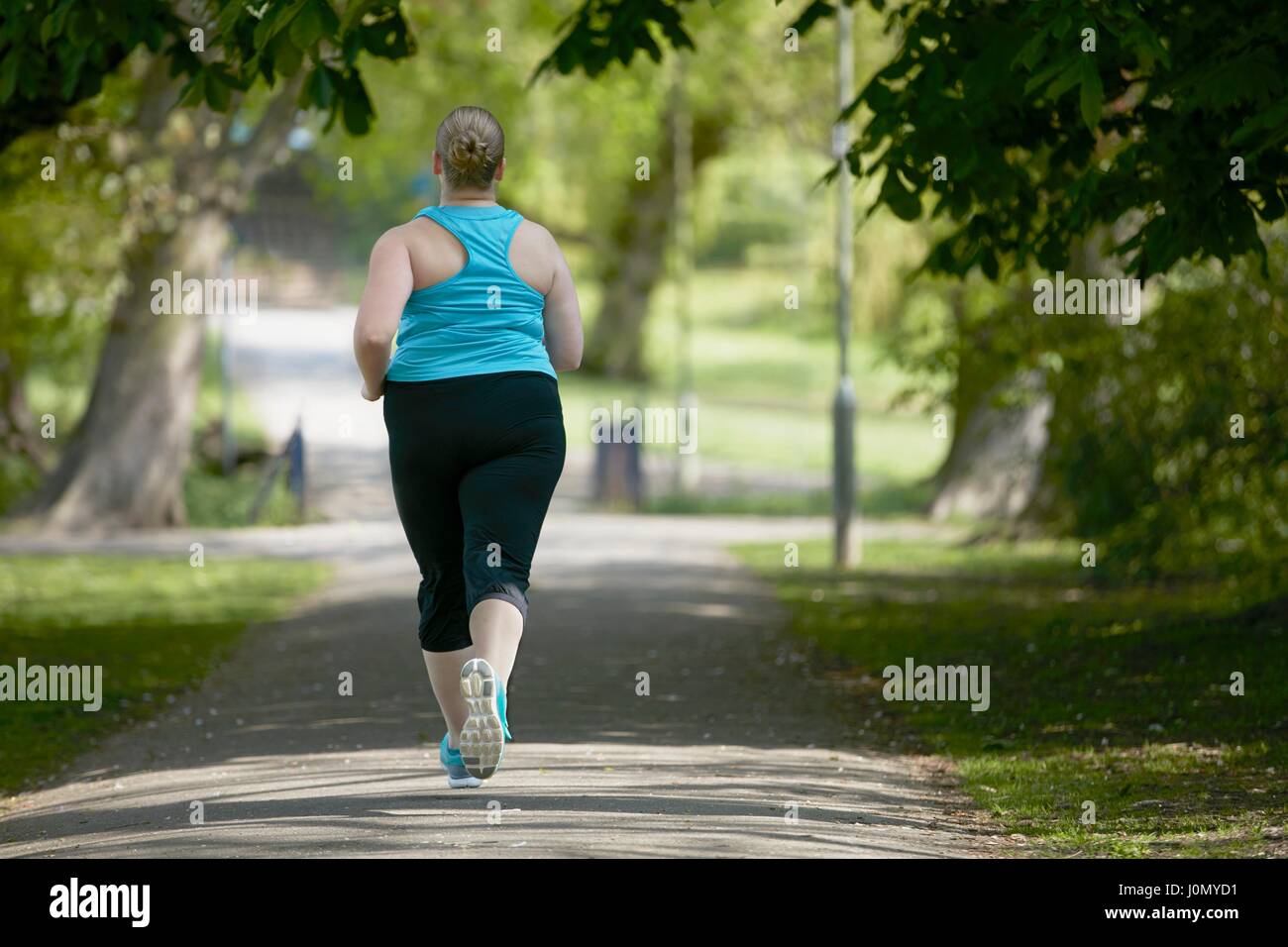Young woman running on path, rear view. Stock Photo