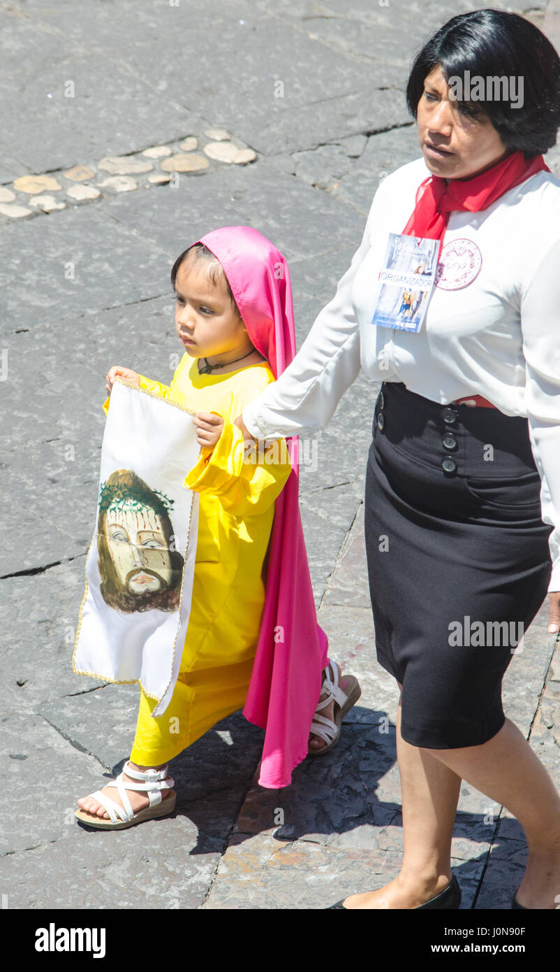 Puebla, Mexico. 14th April 2017. A little girl dressed in traditional costume carries an image of Jesus Christ during the Easter procession in the centre of Puebla in Mexico. The procession is said to be the largest in Latin America and started from the cathedral. Credit: rsdphotography/Alamy Live News Stock Photo