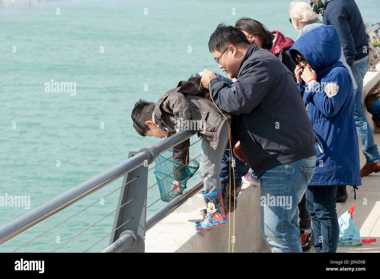 Children and adults try to catch crabs at the harbour in Littlehampton