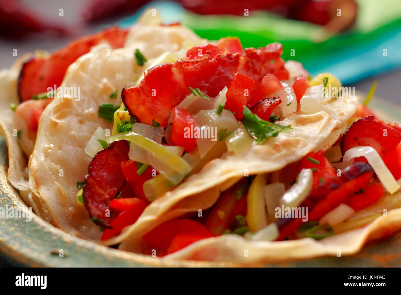 Close-up of wraps filled with fried bacon, chopped yellow bean pods, pepper, onion and parsley Stock Photo