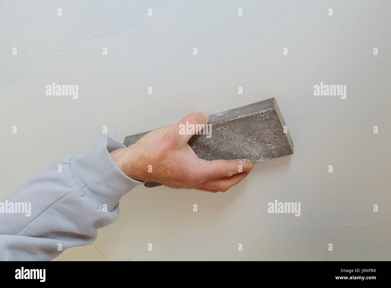 plastering man hand sanding the plaste in drywall seam plasterboard