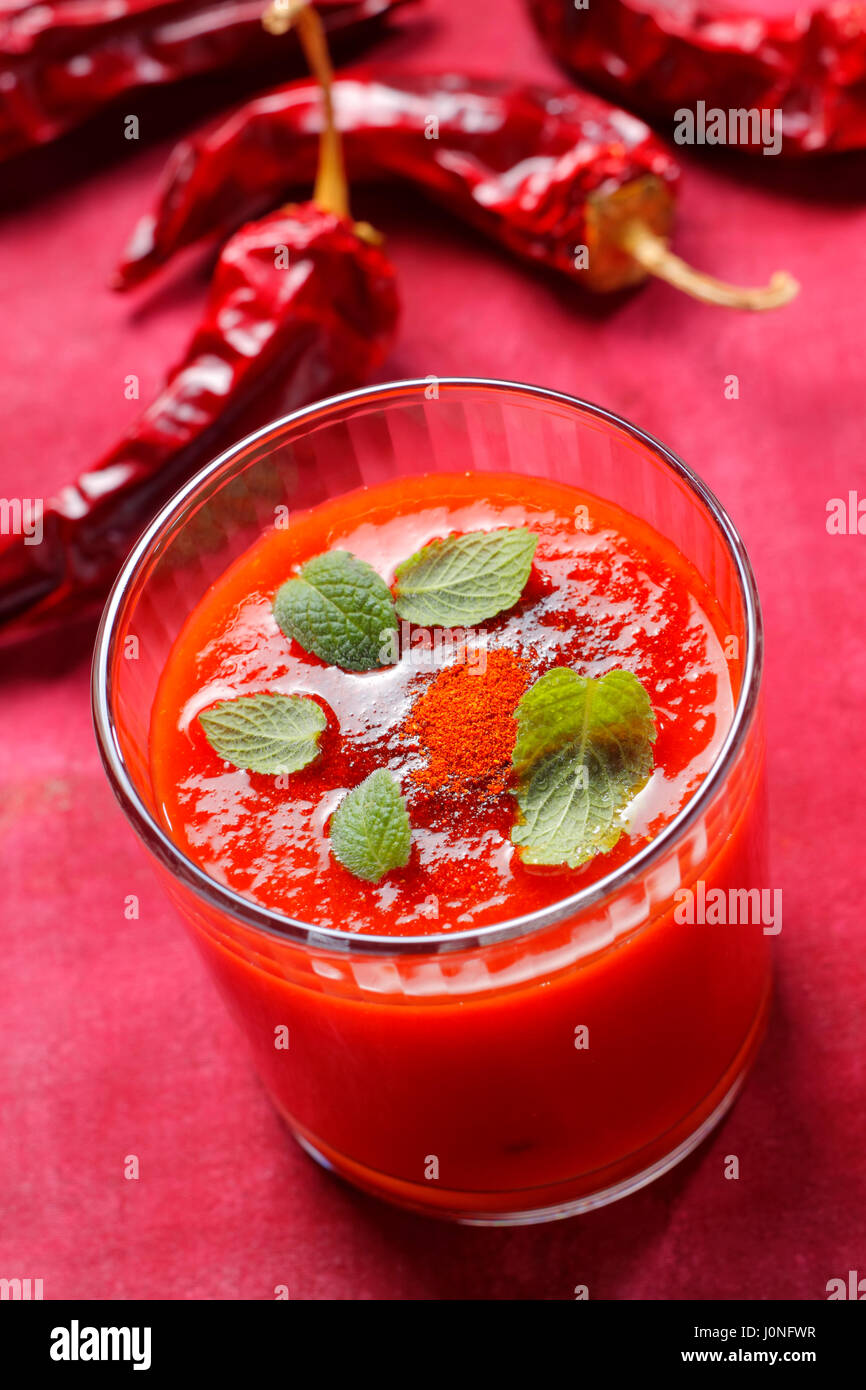 Spicy tomato soup in glass with mint leaves and ground paprika Stock Photo