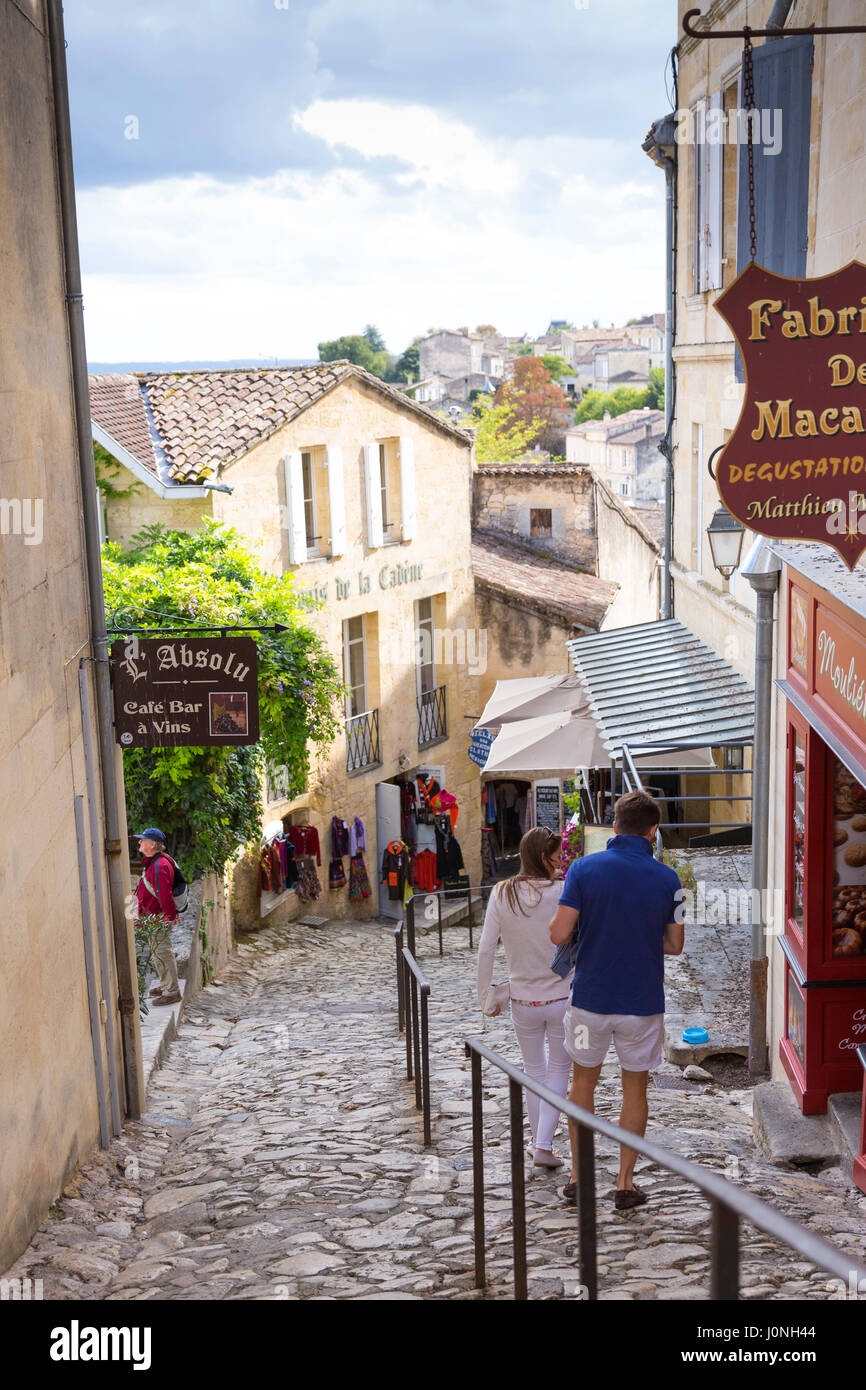 Tourists in cobbled street scene passing shops in the town of St Emilion, famous for wine production, France Stock Photo