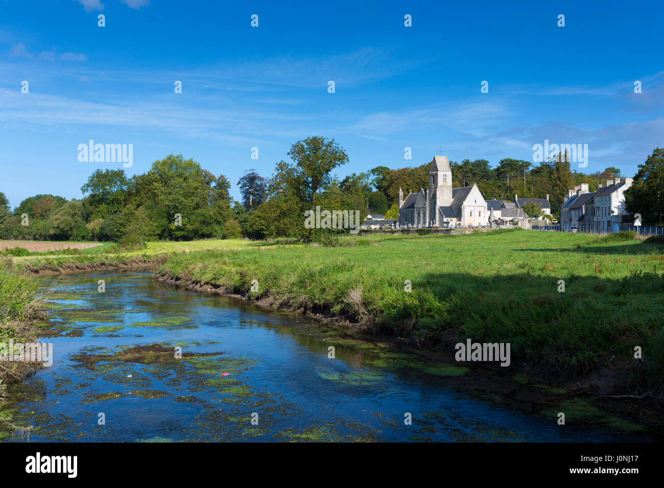 Ancient typical Norman church by the river at Vaux-sur-Aure in Normandy Stock Photo