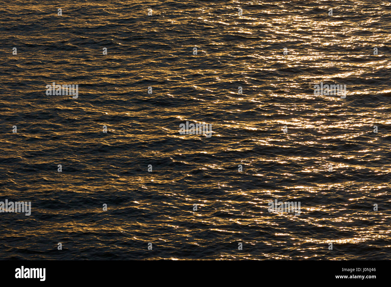 Sun on water - close up of ripples, gentle waves and sunlight reflecting on the surface of the ocean Stock Photo