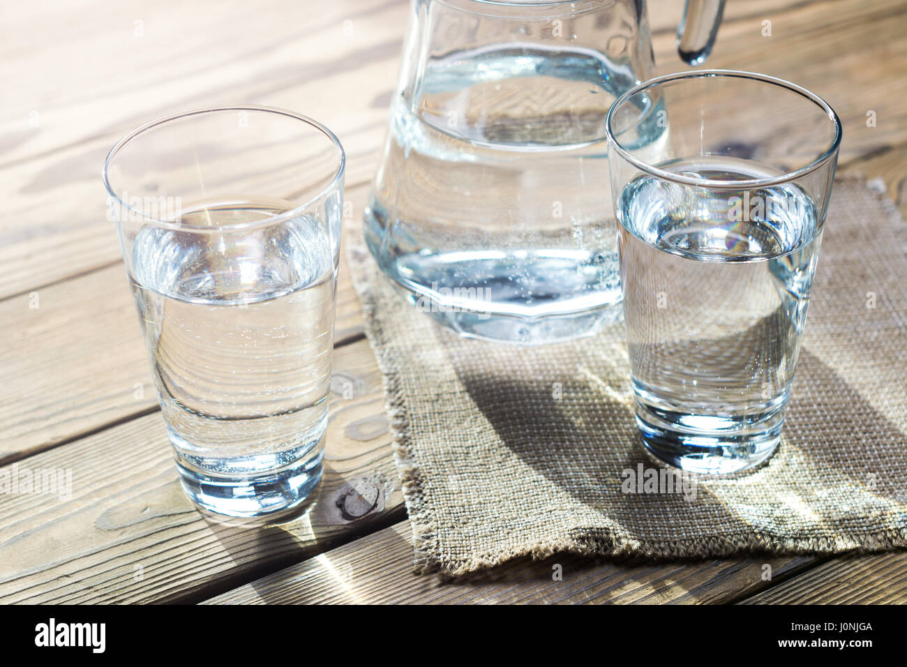 Glasses of water on a wooden table. Selective focus. Shallow DOF. With light effects. Stock Photo