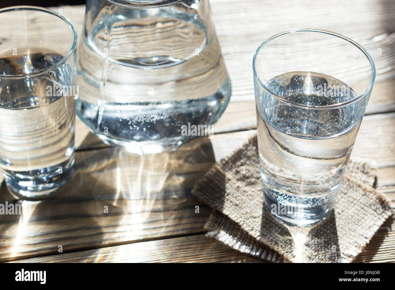 Glasses of water on a wooden table. Selective focus. Shallow DOF. With light effects. Stock Photo