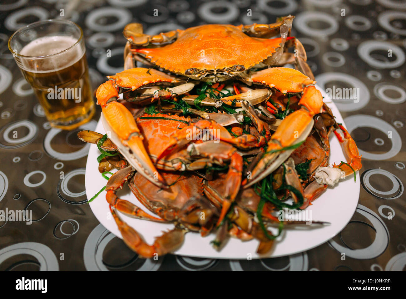 Mount cooked blue crabs in a bowl on a table with beer. Stock Photo