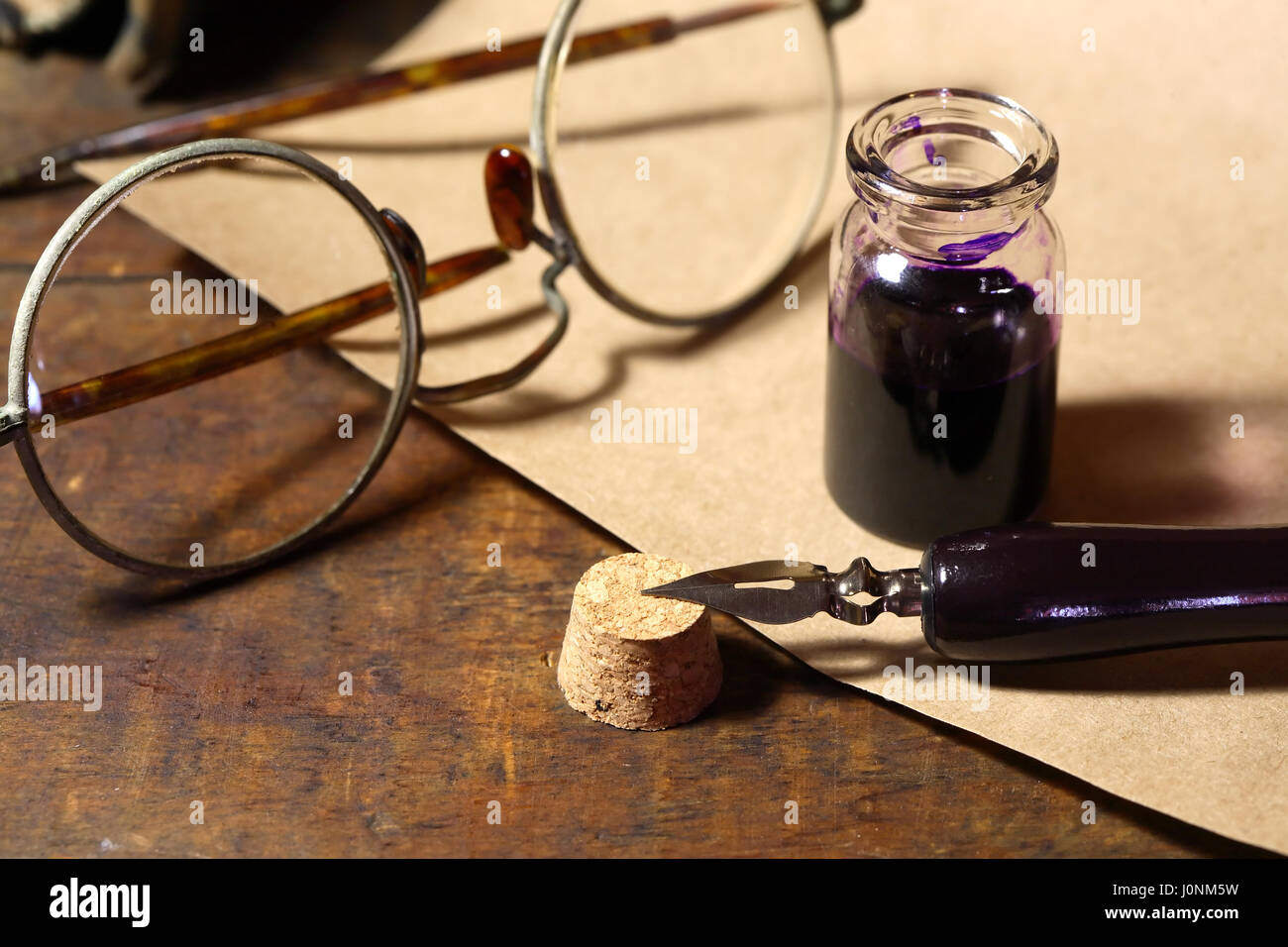 Vintage still life with inkpot and pen near scroll on wooden table ...