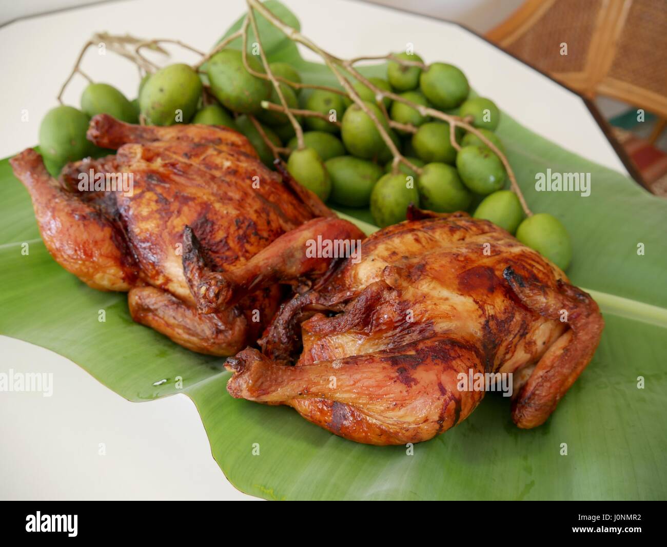 Roasted chicken (lechon manok) and green mangoes  “lechon manok” or roasted chicken is a favorite of many, especially with the Filipinos. Stock Photo