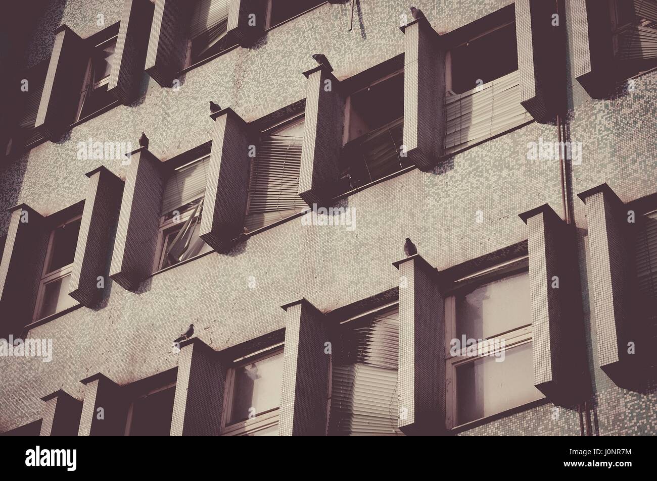 Abandoned high building with broken windows. Sepia Film effect Stock Photo