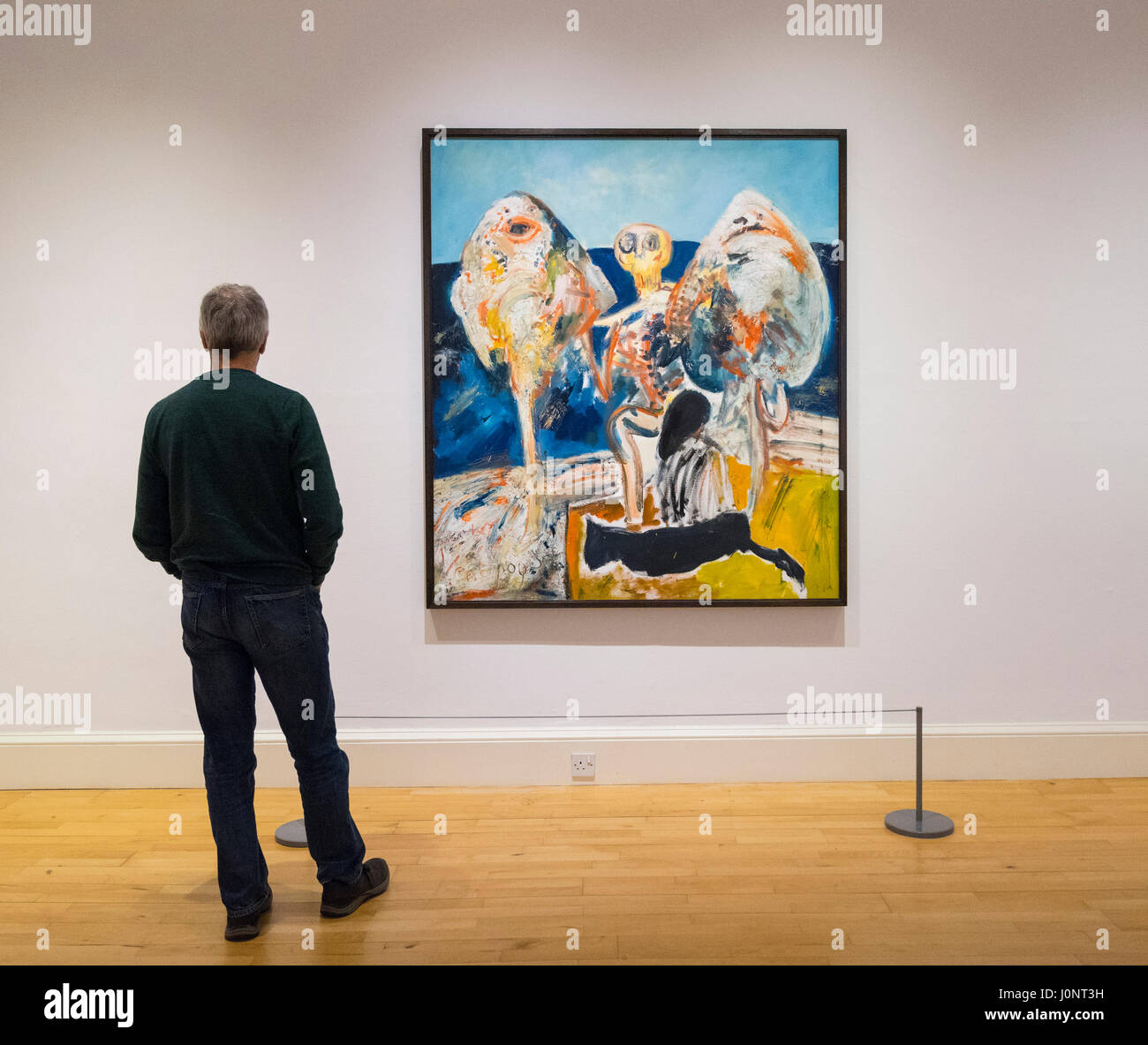 Man looking at painting The Ventriloquist by John Bellamy on display at