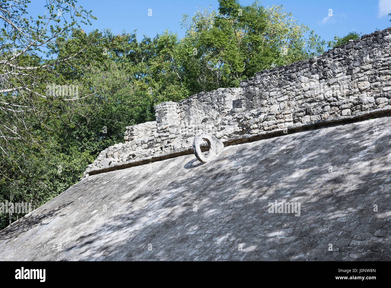 the sloping side of a Ball Court with stone ring at top for goal at the Mayan Coba Ruins Mexico Stock Photo