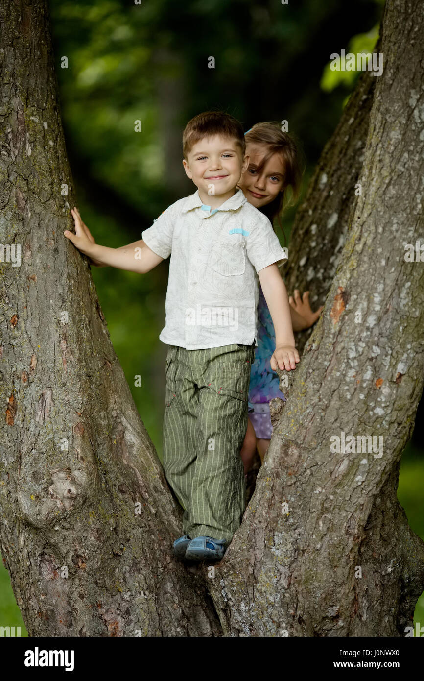 boy and girl climb big tree Stock Photo