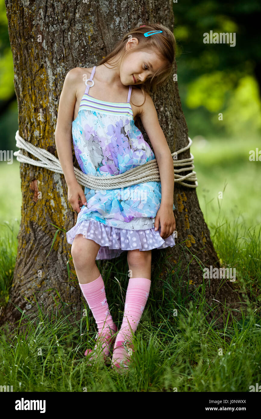 girl tied to tree in park Stock Photo