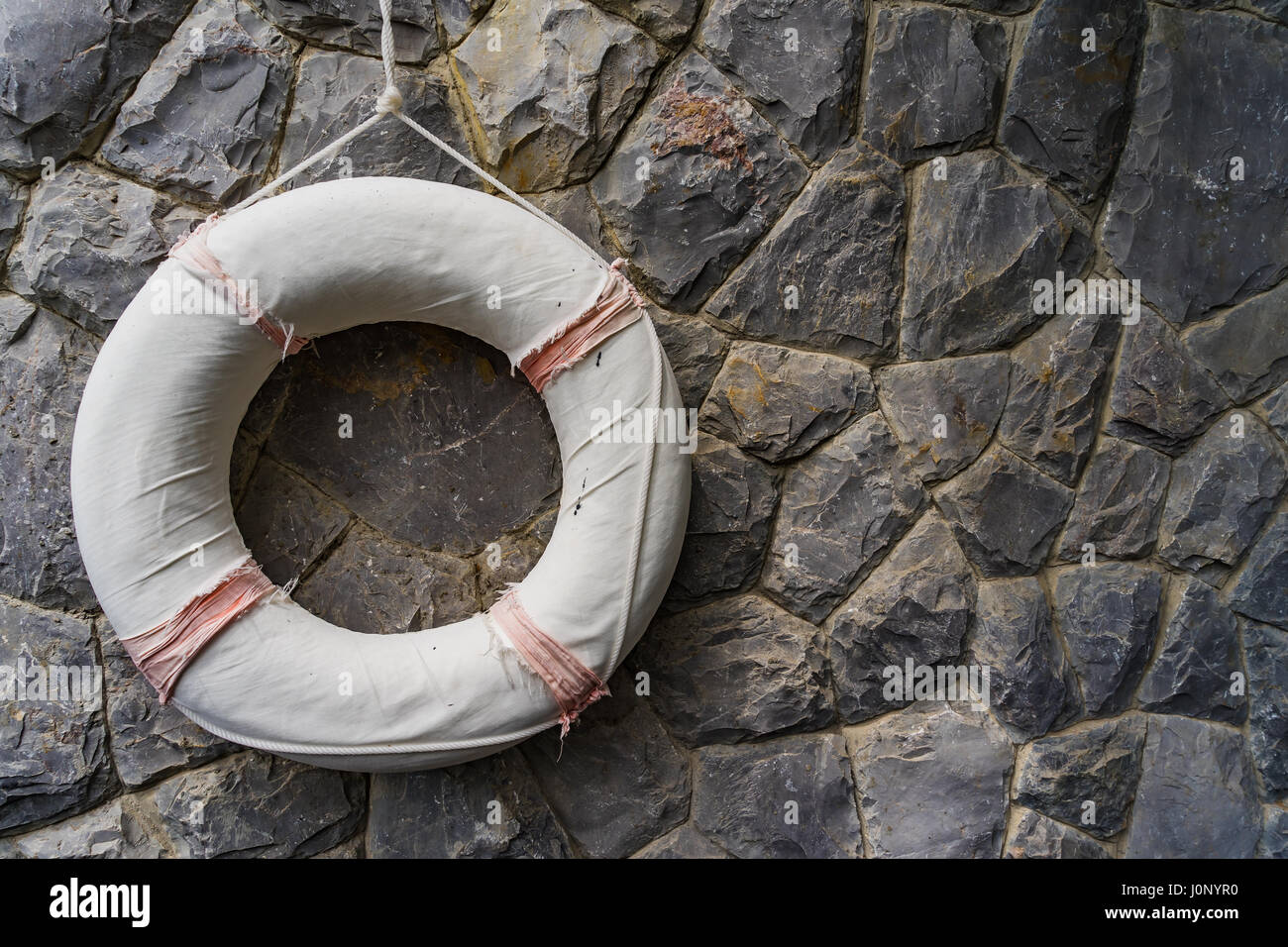 Life saving rubber, Lifebuoy hanging on rock wall, stone wall Stock Photo Alamy