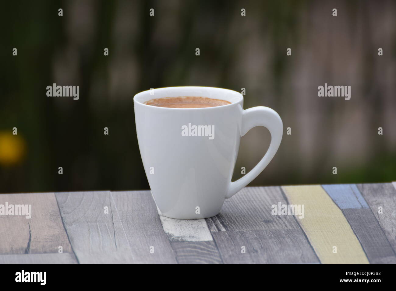 Cup of coffee on wooden table outside Stock Photo