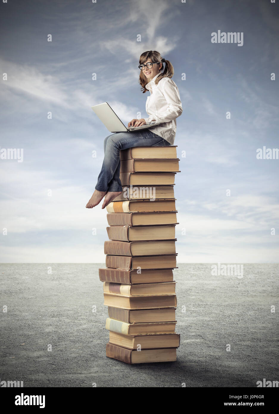 Student girl sitting on pile of books Stock Photo - Alamy