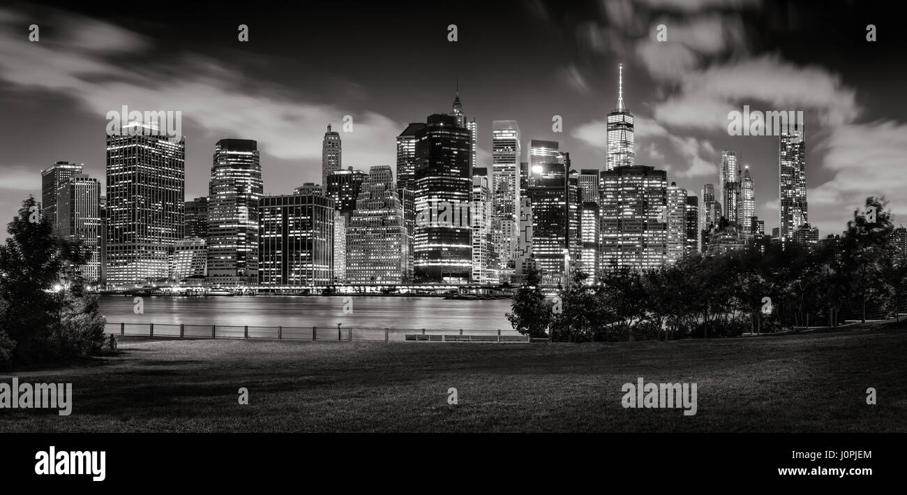 Lower Manhattan skyline and Brooklyn Bridge Park at twilight with illuminated skyscrapers of the Financial District. New York City (Black & White) Stock Photo