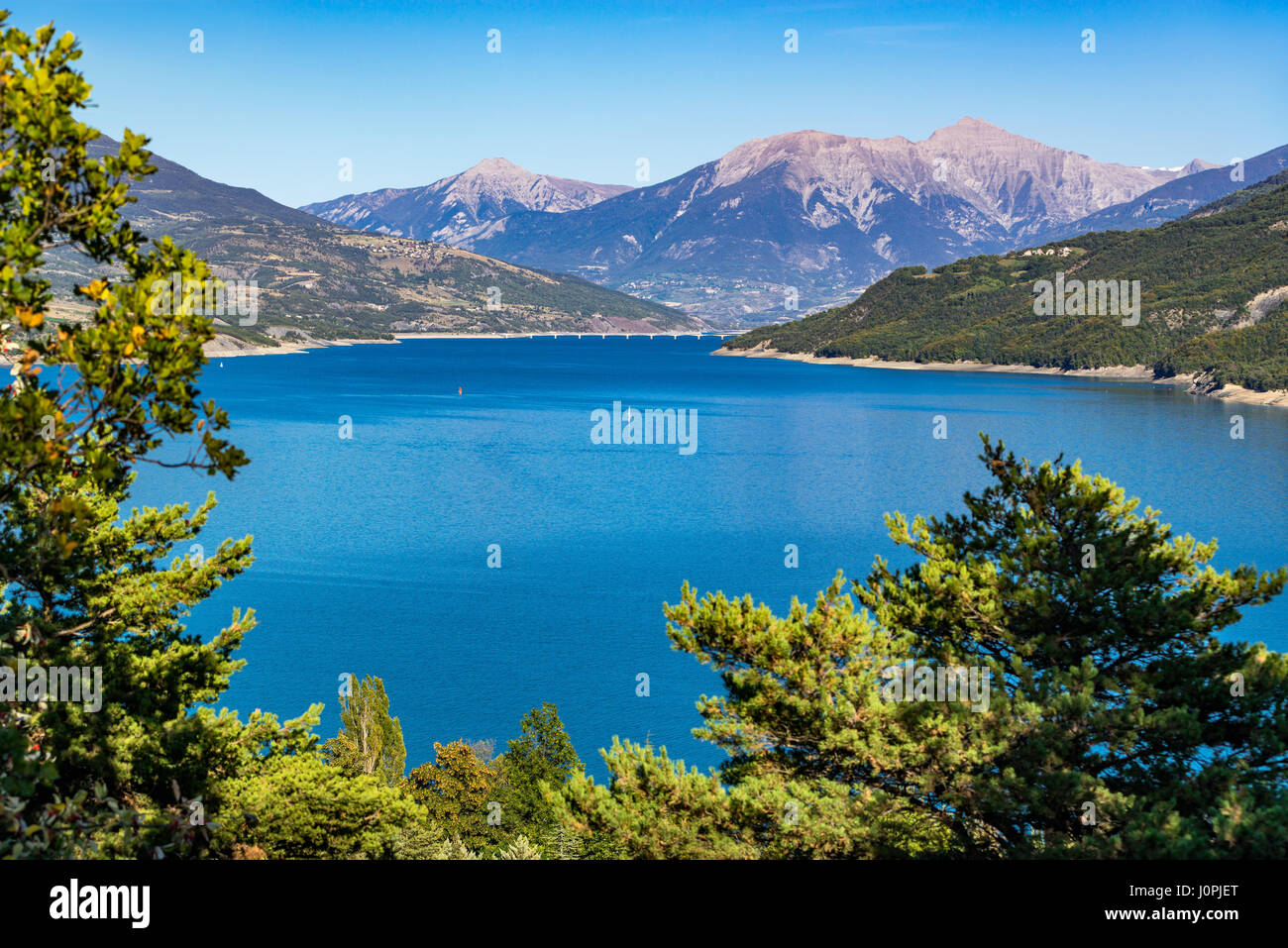 Serre-Poncon lake in Summer with the Savines-le-Lac bridge in the distance. Hautes-Alpes, Paca region, Souther French Alps, France Stock Photo